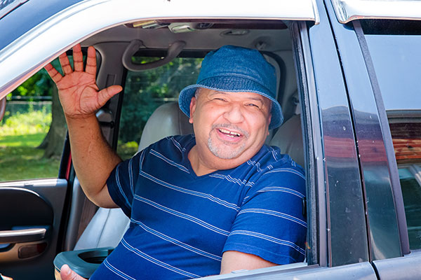 man waving in his car