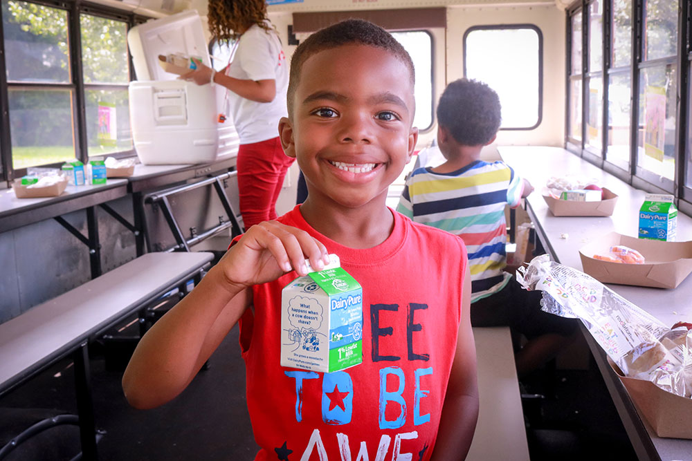 feeding-kids-main young boy smiling holding a carton of milk