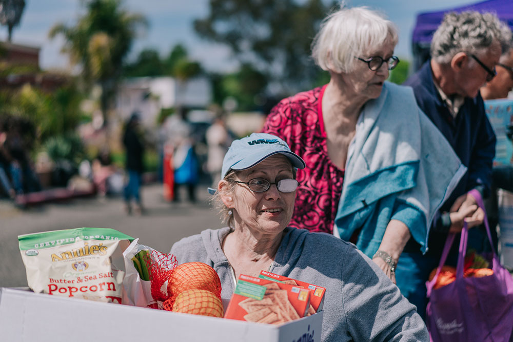 feeding-seniors-main older woman in a wheel chair with a box of food in her lap