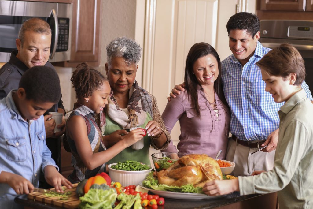 Diverse family in home kitchen cooking Thanksgiving dinner.
