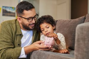 Father and son putting coin into piggy bank.